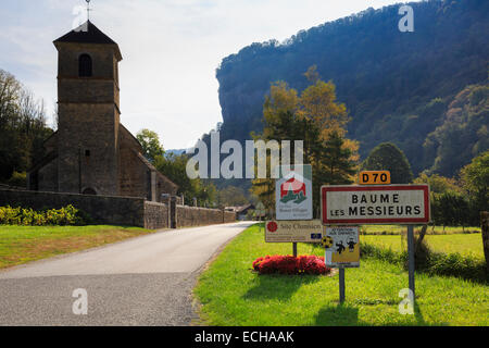 Panneau du village et l'église ci-dessous dans l'escarpement du Jura sur D70. Baume-les-Messieurs, Jura, Franche-Comté, France, Europe Banque D'Images