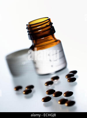 Une petite bouteille en verre avec des comprimés dispersés prises avec une faible profondeur de champ Banque D'Images