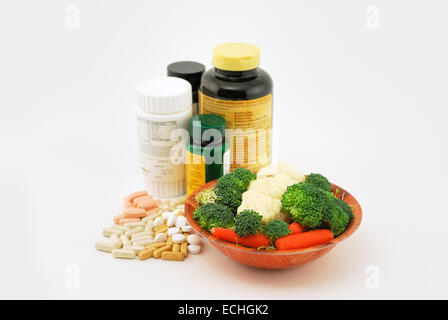 Suppléments, vitamines et des légumes crus utilisés pour un style de vie sain, isolé sur un fond blanc. Banque D'Images