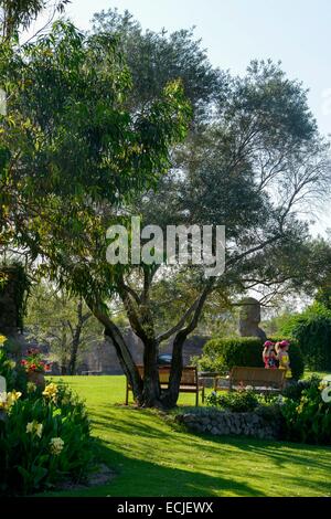 La France, l'Hérault, Béziers, Saint Adrien's garden, classé jardin remarquable (Jardin remarquable), jardin paysagé créé dans une carrière datant du Moyen-Âge, les filles sur une pelouse au pied d'un arbre en face de bancs Banque D'Images