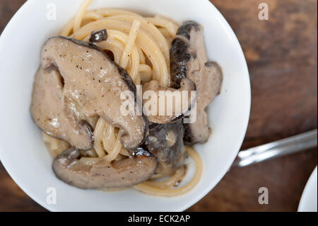 Les pâtes spaghetti italien et des champignons sauvages sur table en bois rustique Banque D'Images