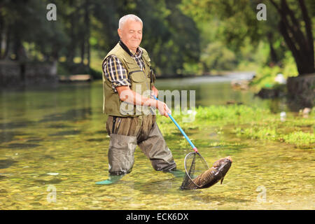 La capture du poisson pêcheur mâle avec net dans une rivière sur un jour d'été ensoleillé Banque D'Images