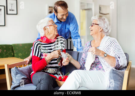 Hauts femme parlant à l'homme tandis que le tricot à nursing home Banque D'Images