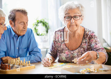 Les personnes jouant des jeux de loisirs à table en maison de soins infirmiers Banque D'Images