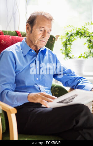 Senior man reading book at nursing home Banque D'Images