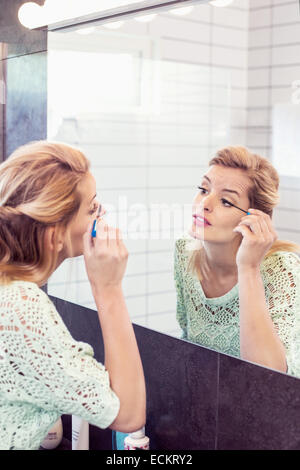 Jeune femme mascara en face du miroir de salle de bains Banque D'Images