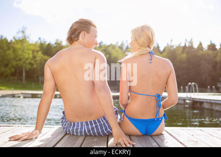 Vue arrière du couple sitting on boardwalk at Lake Banque D'Images