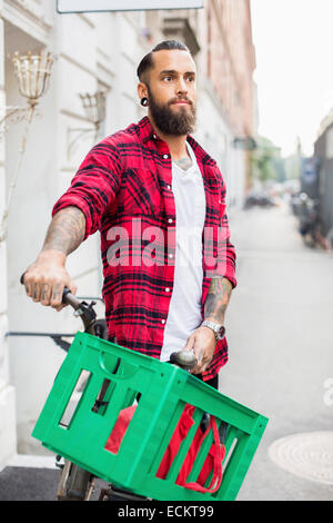 Propriétaire d'un vélo debout sur un trottoir par candy store Banque D'Images