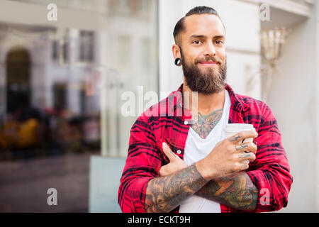 Portrait of smiling propriétaire avec du café à l'extérieur de magasin de bonbons Banque D'Images