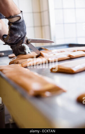 Portrait of worker cutting caramel avec des ciseaux dans candy store Banque D'Images