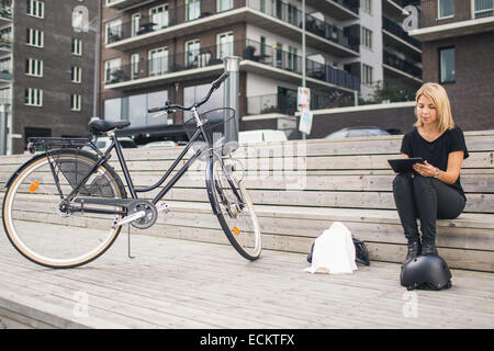 Toute la longueur de businesswoman using digital tablet while sitting on steps in city Banque D'Images