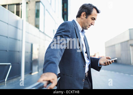 Businessman using mobile phone on sidewalk Banque D'Images