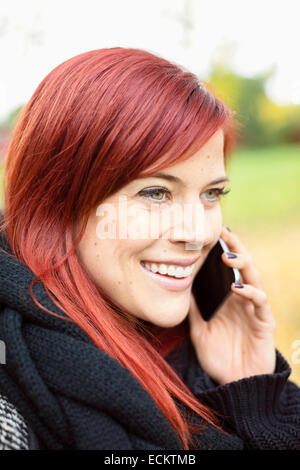 Happy Mid adult Woman talking on smart phone in park Banque D'Images