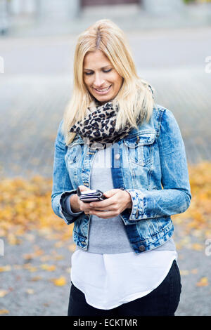 Smiling Mid adult woman using smart phone in park Banque D'Images