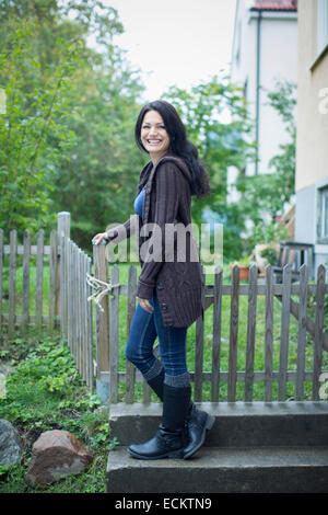 Full Length portrait of mid adult woman standing by railing in yard Banque D'Images