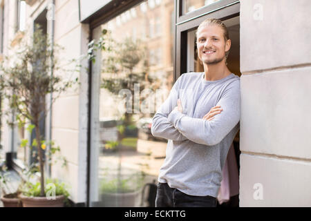 Portrait of owner leaning on wall, magasin de vêtements Banque D'Images
