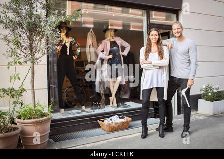 Portrait of smiling propriétaire avec femme debout devant une boutique de vêtements Banque D'Images