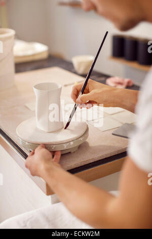 Les jeunes hommes de la poterie dans l'atelier de peinture de la vaisselle Banque D'Images