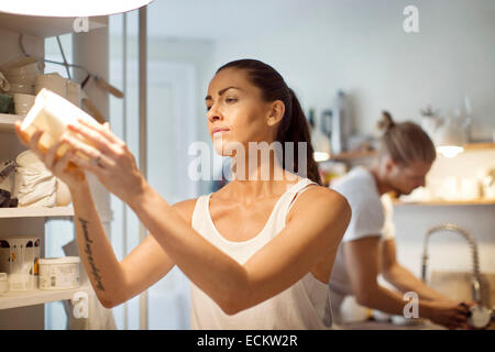 Travailleur féminin à la vaisselle à tout collègue masculin travaillant en atelier Banque D'Images