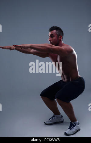 Athletic jeune homme musclé faisant s'accroupit Banque D'Images