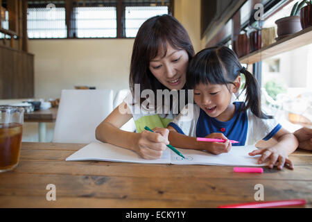 La mère et la fille assis à une table, dessin avec feutres, souriant. Banque D'Images