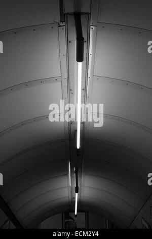 Photographie en noir et blanc du plafond dans le métro de Londres avec escalier genre science-fiction de la lumière sur elle Banque D'Images