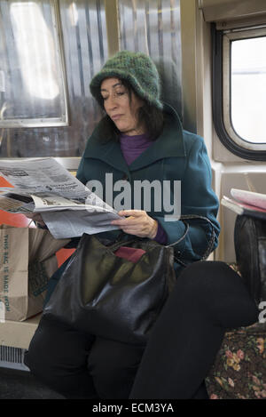 Femme lit un document papier alors qu'une rame de métro à Brooklyn, New York. Banque D'Images