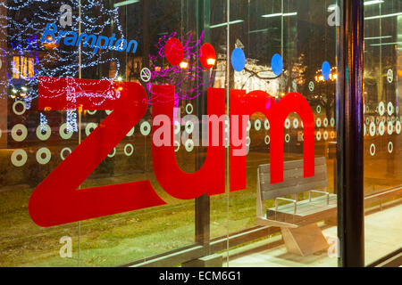 Le transport en commun rapide Züm logo avec les lumières de Noël reflète dans la vitre. Le centre-ville de Brampton, Ontario, Canada. Banque D'Images