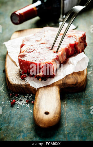 Marbré de steak de boeuf avec une bouteille de vin et un verre de vin sur fond sombre Banque D'Images