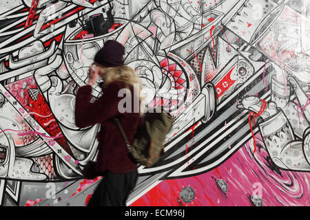 La jeune fille de New York trouble marche pour travailler le long du côté du Bas-est après une fresque d'art peinte colorée et animée Banque D'Images