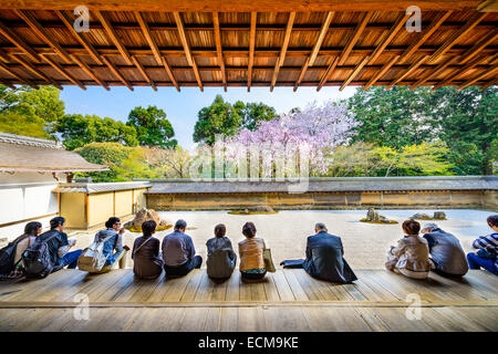 Les touristes s'asseoir et observer le printemps des cerisiers de Ryoan-ji à Kyoto, Japon. Banque D'Images