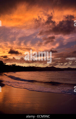 Nuages rouges au coucher du soleil qui se reflète sur la plage de sable humide Maimon Bay Riu beach resort en République Dominicaine Banque D'Images