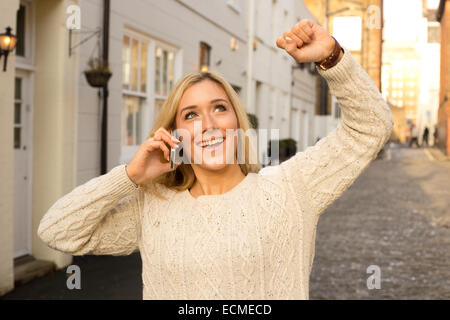 Happy young woman celebrating au téléphone Banque D'Images