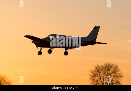 Piper PA28 Cherokee landing au coucher du soleil. G-BYSP Banque D'Images