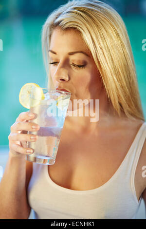 Fille de boire dans un verre d'eau glacée au citron Banque D'Images
