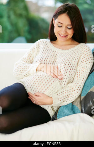 Femme enceinte sat relaxing on sofa Banque D'Images