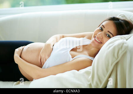 Femme enceinte sat relaxing on sofa Banque D'Images