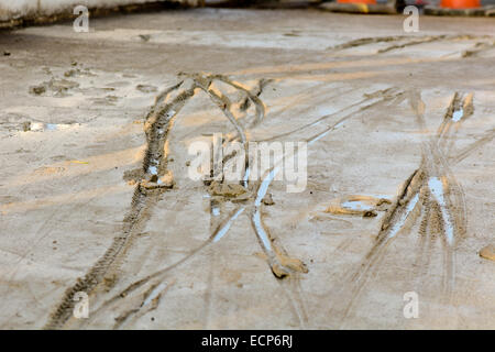 Les traces de pneus de bicyclettes en béton humide frais Banque D'Images