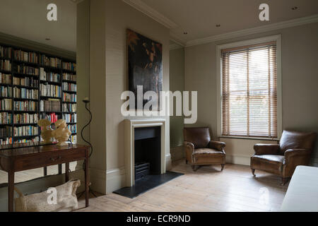 Peinture à l'huile au-dessus de cheminée dans un minimum d'un salon avec fauteuils en cuir et de vieux murs en miroir Banque D'Images