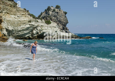 Woman paddling on beach ci-dessous Mamma Mia chapelle, Agios Ioannis, Skopelos, Grèce. Octobre. Au sommet du rocher de l'église Banque D'Images