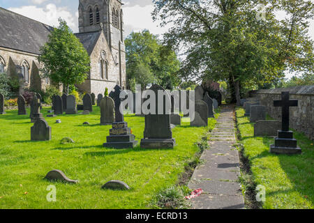 Un chemin menant à travers l'église cimetière passé croix en pierre et pierres tombales. Banque D'Images