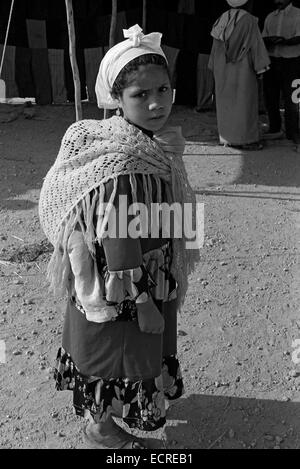 La montagne du Moyen Atlas, Maroc - Juillet 1979 - Une fille épaule son dos à son jeune frère dans un marché berbère, juillet 1979, Banque D'Images