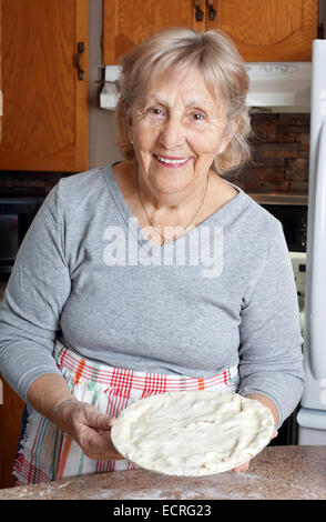 Happy senior femme ou grand-mère montrant des pâtés à la viande dans sa cuisine Banque D'Images