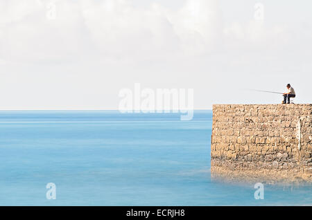 L'homme à la pêche dans l'océan au large de la jetée de pierre Banque D'Images