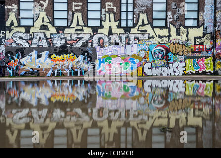 Graffiti sur un bâtiment reflète dans l'eau Banque D'Images