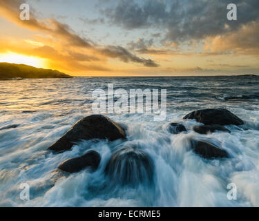 Se précipitant sur les rochers de l'eau au coucher du soleil Banque D'Images