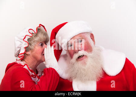 Mrs Claus chuchote un secret à l'oreille du père Noël. Elle sait peut-être qui a été Gentil ou méchant. Banque D'Images