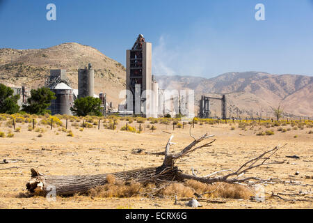Une cimenterie à Tehachapi Pass, Californie USA, avec la sécheresse a tué les arbres en premier plan. La production de ciment est l'un des la plupart des émissions des industries de la faim sur la planète, le changement climatique et la conduite menant à la sécheresse. Banque D'Images
