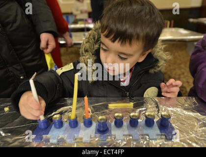 Merrick, New York, USA. Dec 18, 2014. Deux ans, BRAD SCHLECHTER, du Merrick, créer sa menorah lorsque le Centre juif de Merrick tente de reprendre le record du monde Guinness pour la plupart des Menorot allumé dans un endroit à la fois que la congrégation en 2011. Le troisième soir de Hanoukka, la 'Light Up the Night 2 - portant le bilan Accueil' event comprenait également une cérémonie de l'allumage des bougies dans le sanctuaire principal. Si la Menorah Lighing objectif d'au moins 1 000 lumière menorot a été manquée, et le dossier n'a pas gagné de retour, plus de 600 menorot étaient allumés à la MJC en même temps. (Crédit Imag Banque D'Images