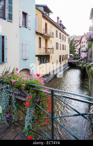 Fleurs colorées sur un pont à Annecy, France avec des bâtiments typiques aux côtés d'une voie d'eau Banque D'Images